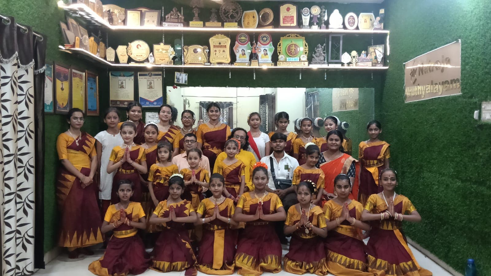 Students and teachers posing beneath the academy trophy display
