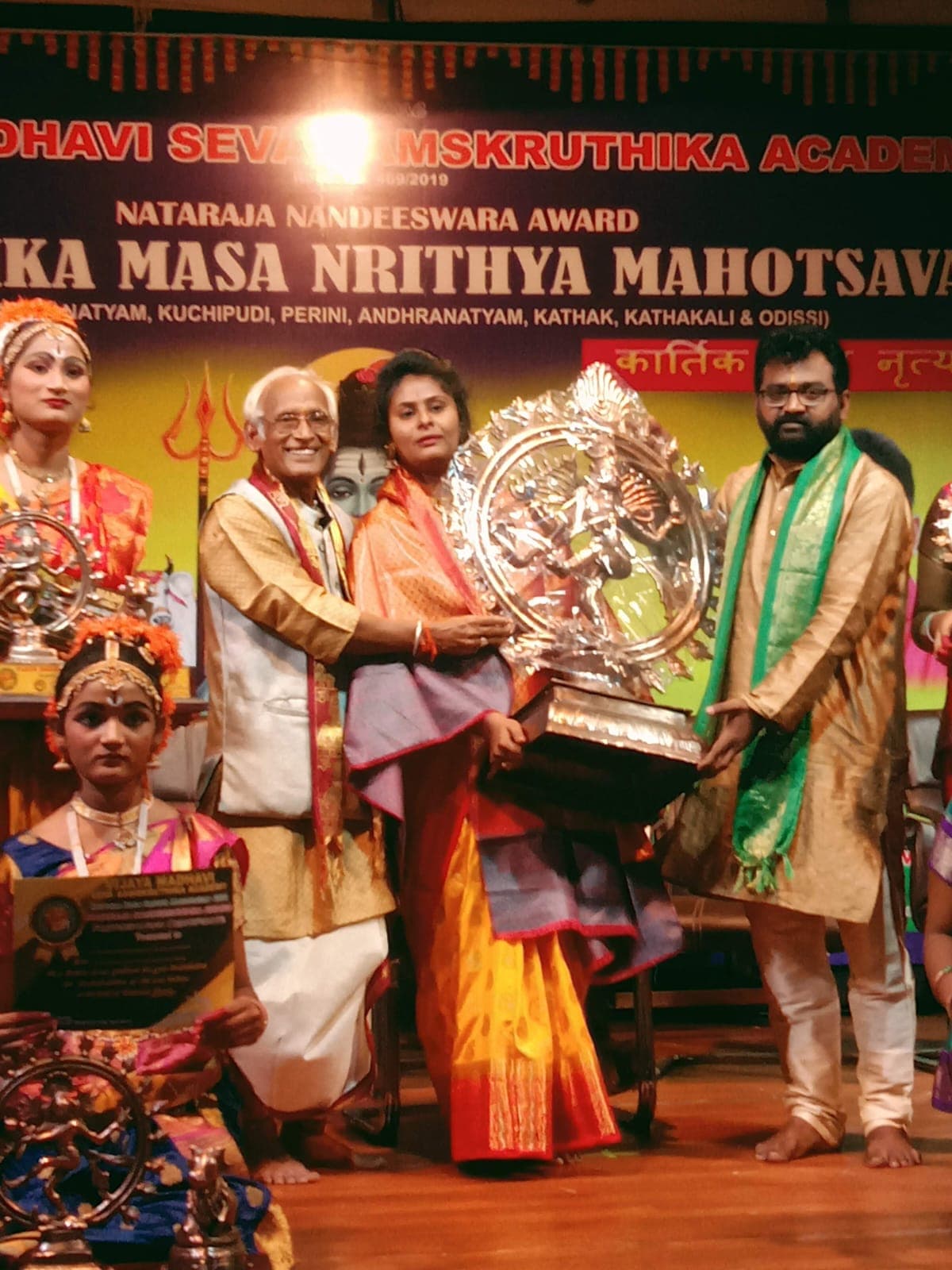 A group presenting a large Nataraja sculpture at a cultural ceremony