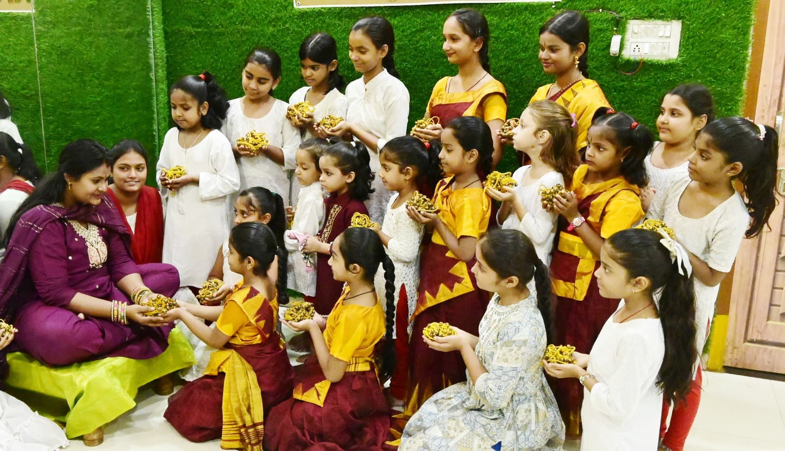 A teacher seated with young dance students at the academy
