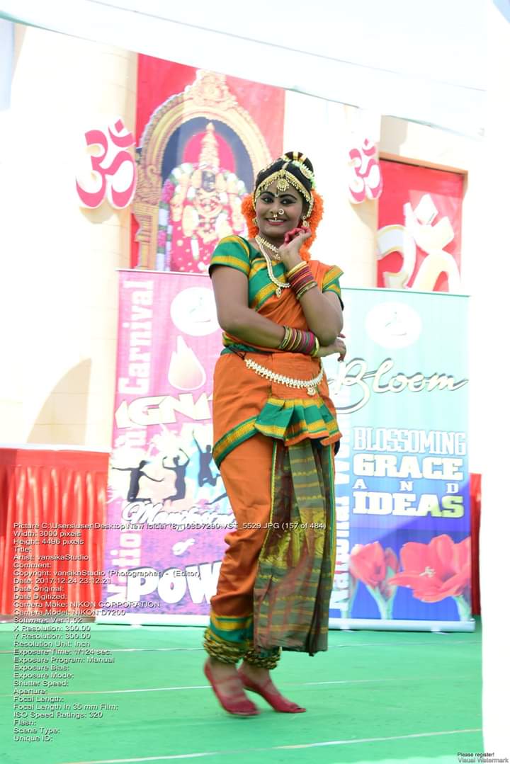 A solo dancer in orange and green costume performing on stage