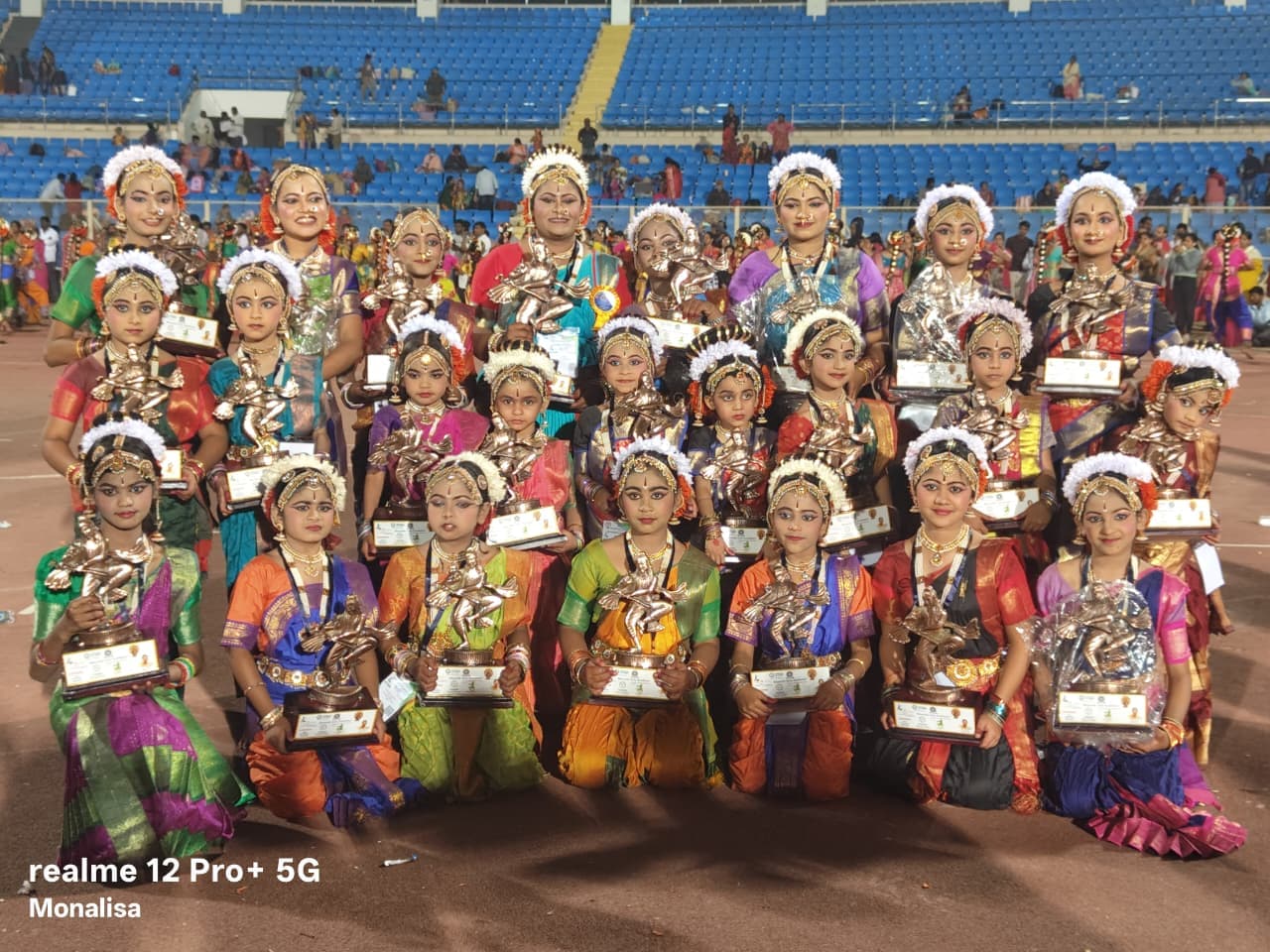 Classical dancers in coordinated costumes gathered in a stadium