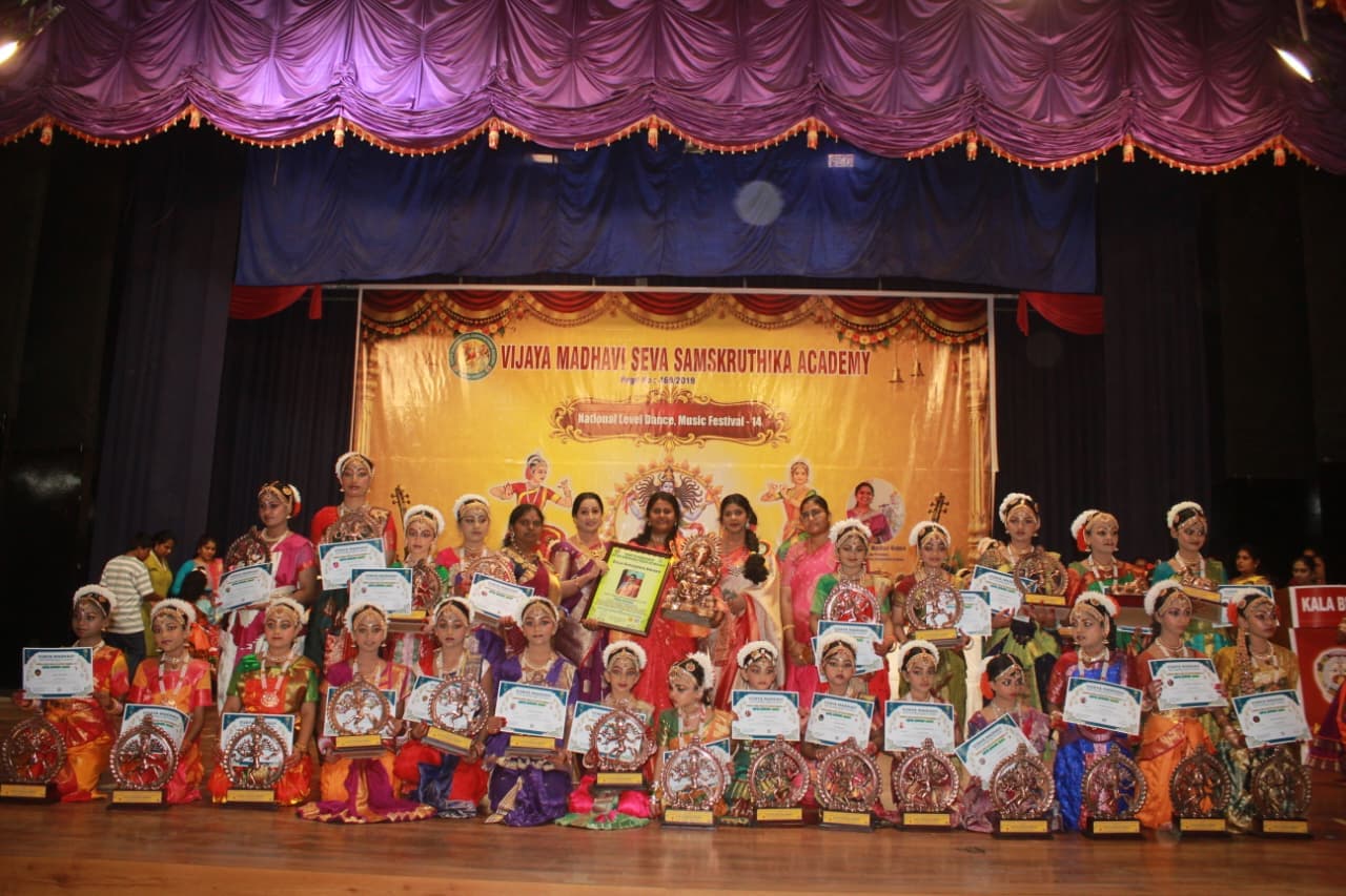 A large group of young dancers displaying certificates on stage