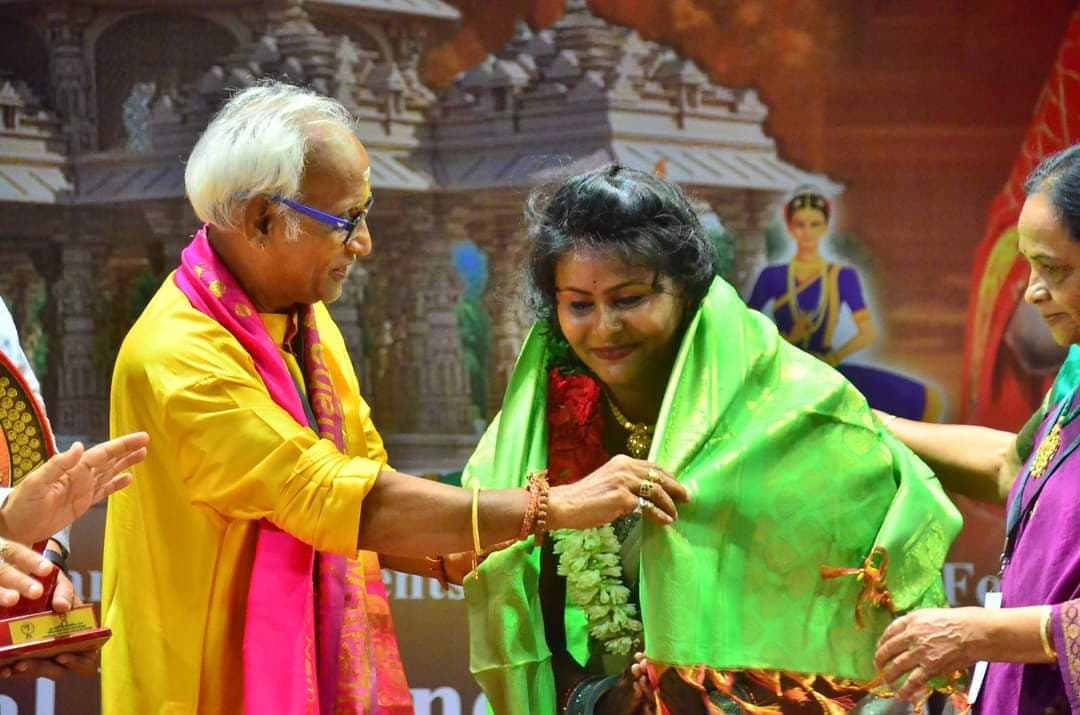 An elder presenting a green ceremonial shawl during an award ceremony
